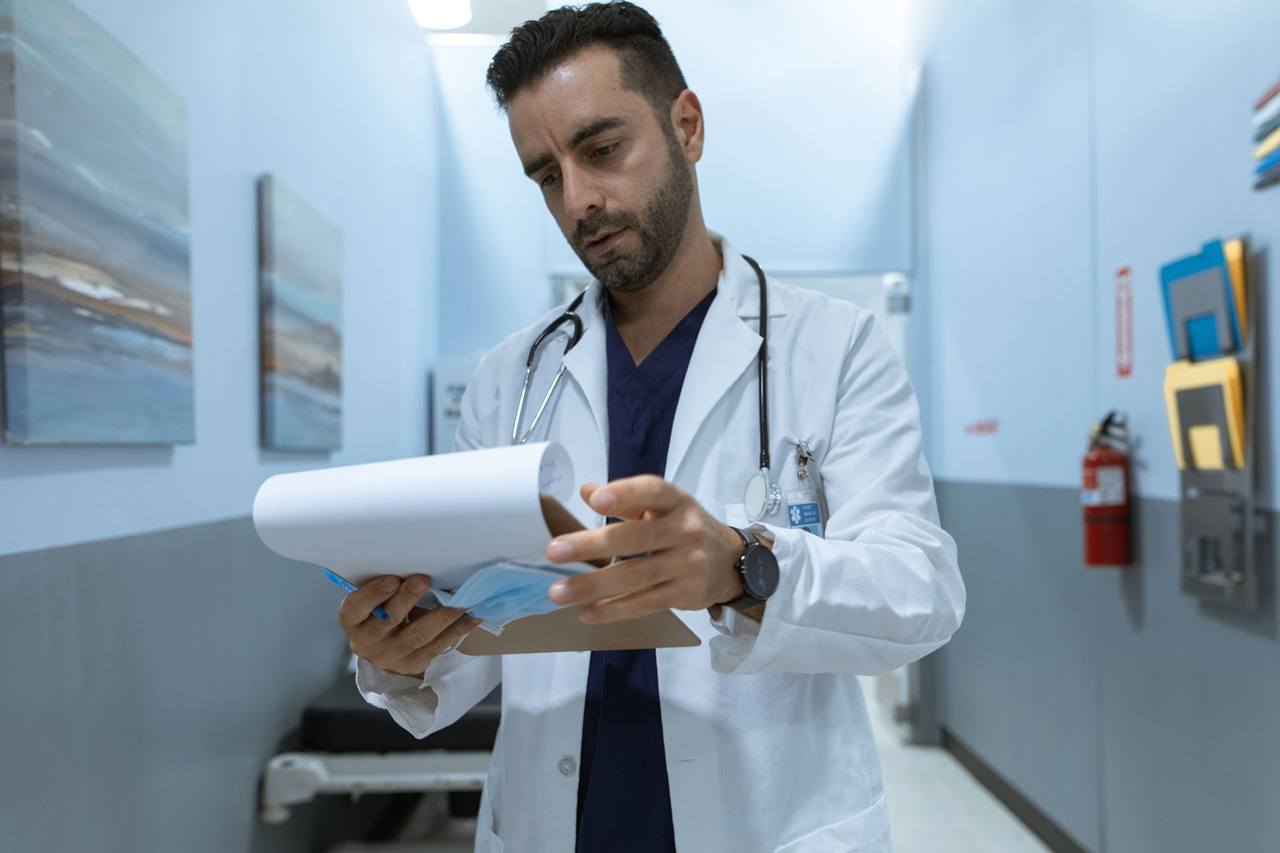A doctor reviewing charts in a hospital corridor